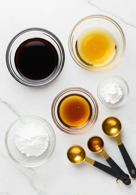 Various ingredients for stir fry sauce including soy sauce, sesame oil, cornstarch, and measuring spoons.