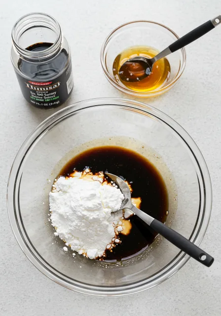 Soy sauce, sesame oil, and cornstarch being combined in a glass bowl to make stir fry sauce.