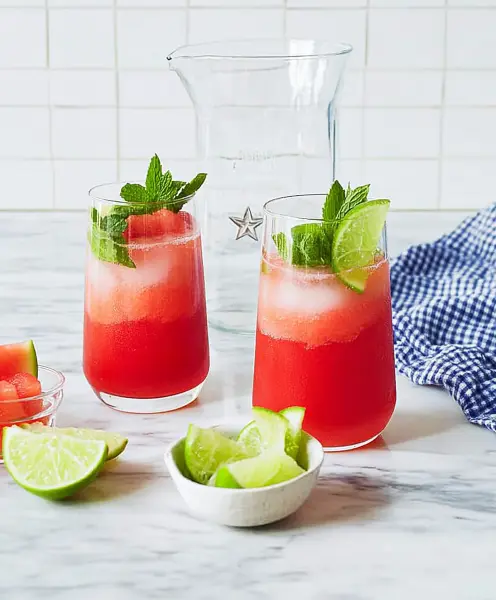 Refreshing watermelon juice in tall glasses with fresh mint and lime, perfect for a hot day.