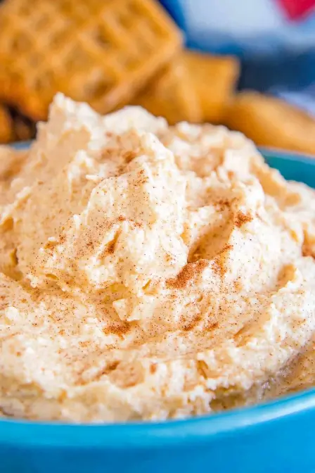 Creamy homemade pumpkin fluff in a blue bowl, lightly dusted with cinnamon, perfect for a fall dessert or dip.