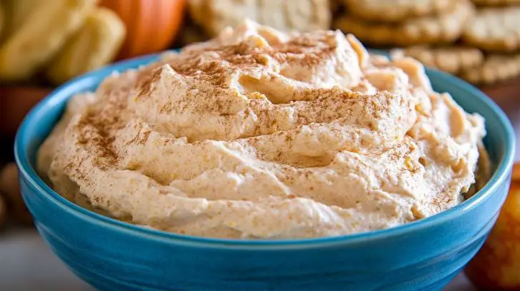 Creamy homemade pumpkin fluff in a blue bowl, lightly dusted with cinnamon, perfect for a fall dessert or dip.