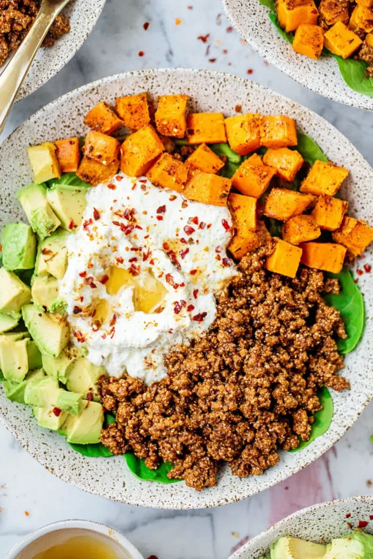Power bowl with ground beef, roasted sweet potatoes, avocado chunks, and whipped ricotta topped with chili flakes