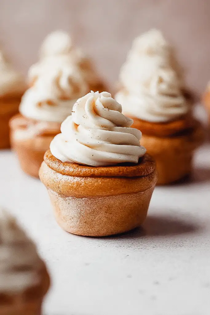 Golden brown cinnamon roll cupcakes topped with swirls of creamy frosting, perfect for a sweet breakfast or dessert treat