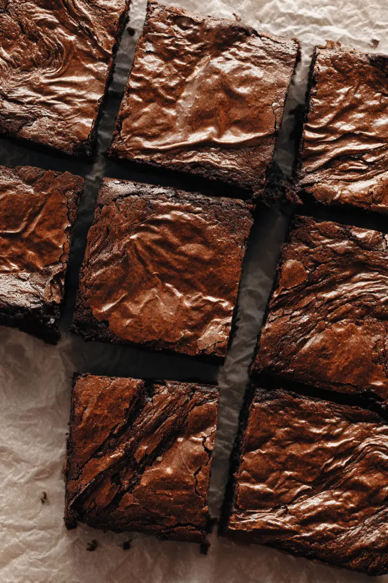 Rich miso caramel brownies with crackly golden tops and gooey centers, sliced and arranged on parchment paper.
