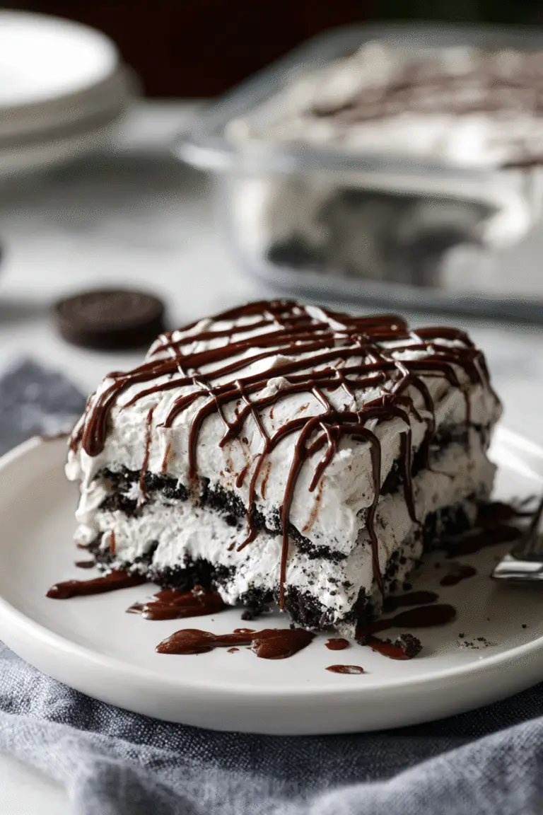 Close-up of a rich Oreo icebox cake slice with creamy layers, crushed cookies, and chocolate drizzle on a white plate