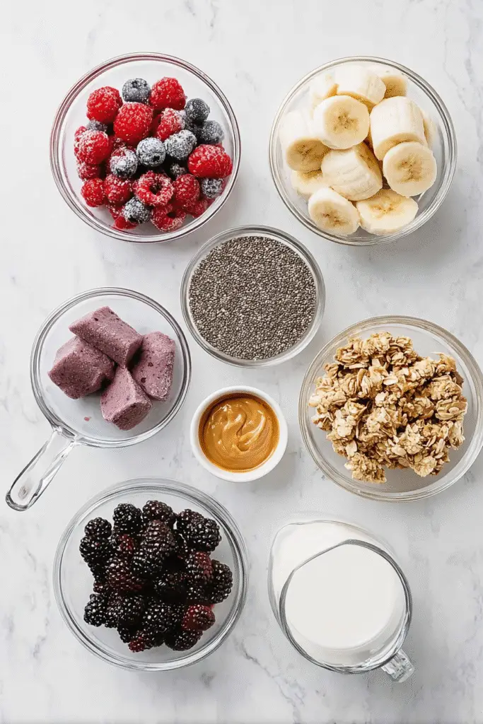 Smoothie bowl ingredients including bananas, berries, granola, chia seeds, peanut butter, and milk arranged in clear bowls