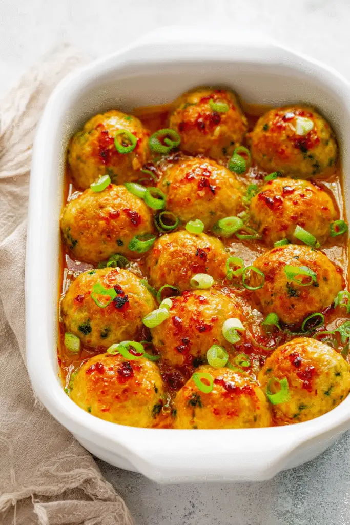 Thai baked chicken meatballs in a white casserole dish,