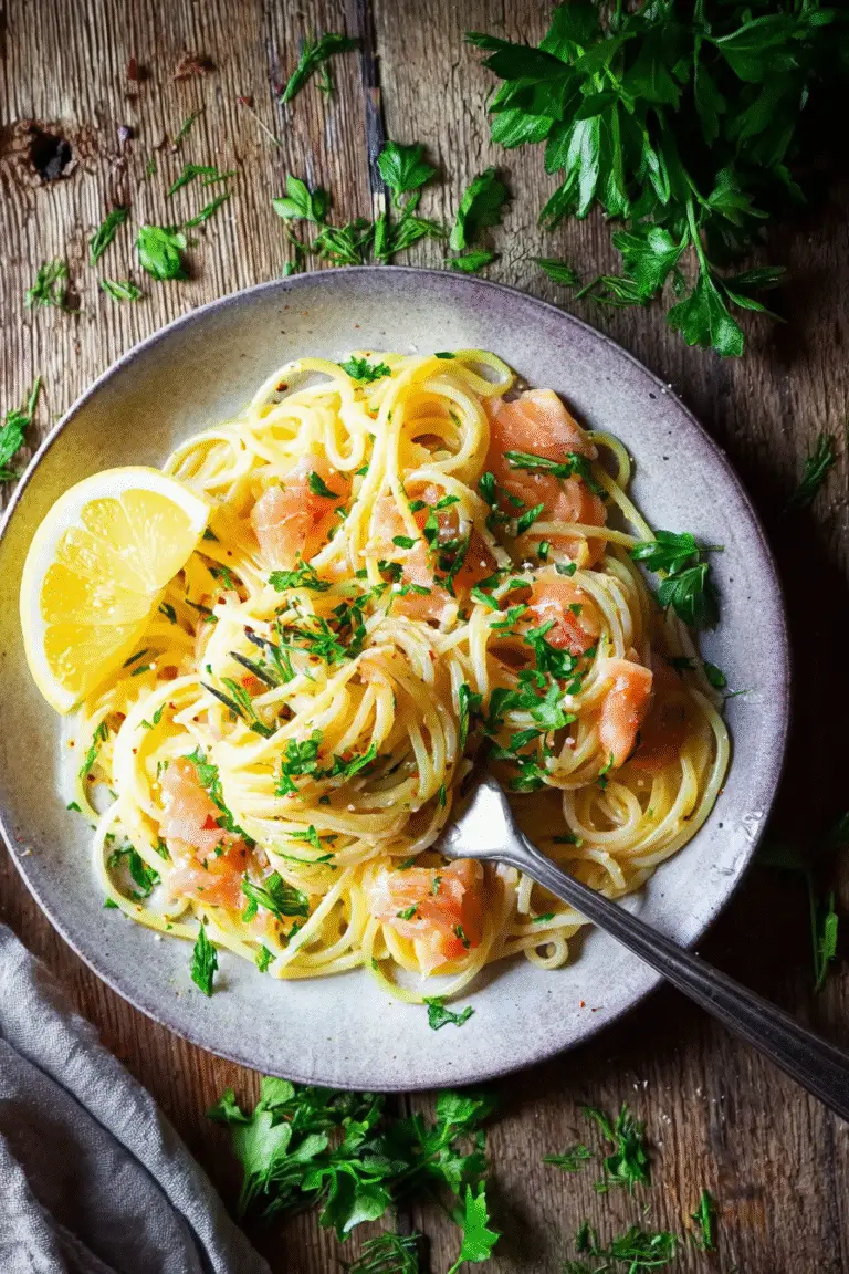 Creamy smoked salmon carbonara with spaghetti, fresh parsley, and lemon wedge on a rustic wooden table.