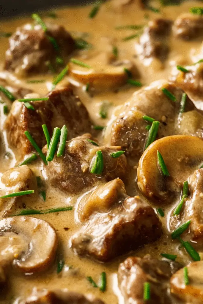 Tender beef pieces in creamy mushroom sauce topped with fresh chives, creating a rich and flavorful beef stroganoff.