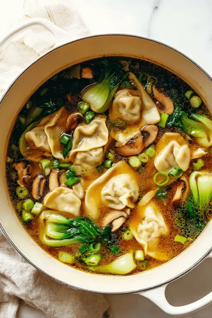 Warm potsticker soup with dumplings, bok choy, mushrooms, and scallions simmering in a flavorful golden broth.