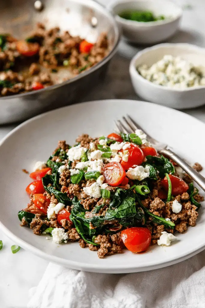 Savory Mediterranean ground beef stir-fry with cherry tomatoes, spinach, and feta on a white plate, ready to serve